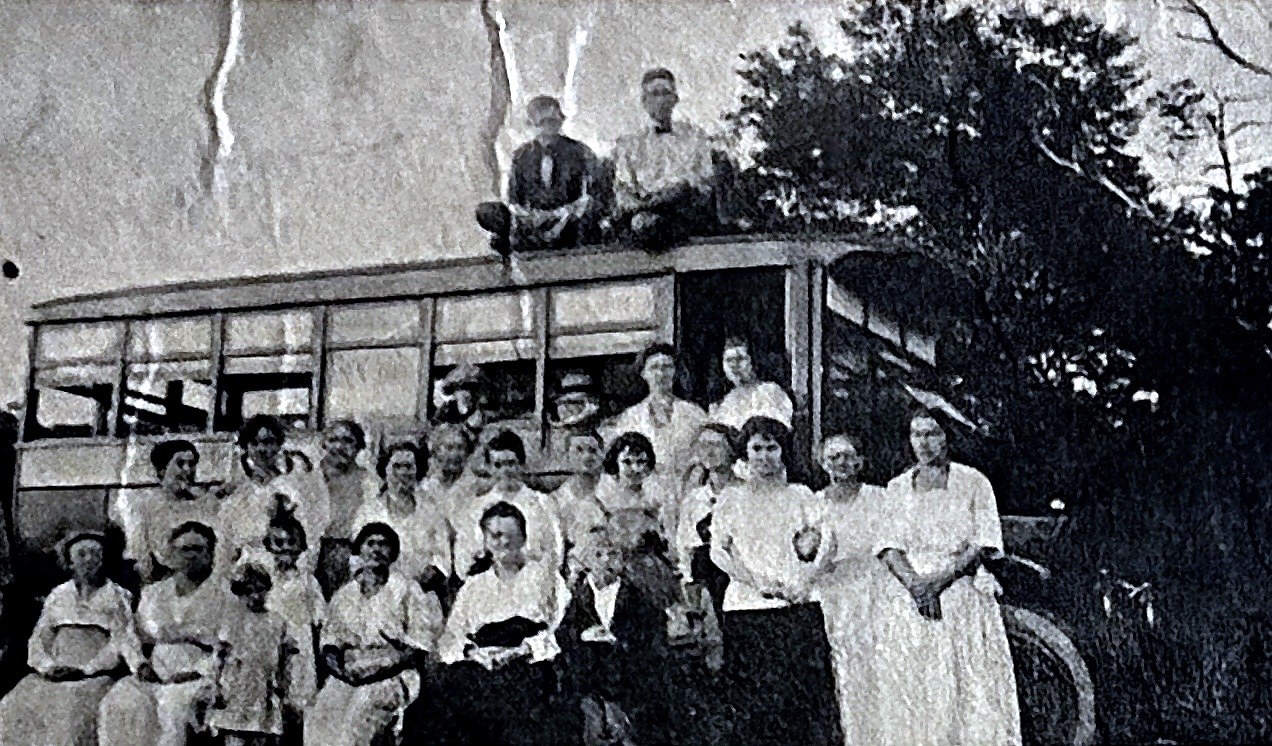 Group posed on and in front of a bus around 1918 to 1920.